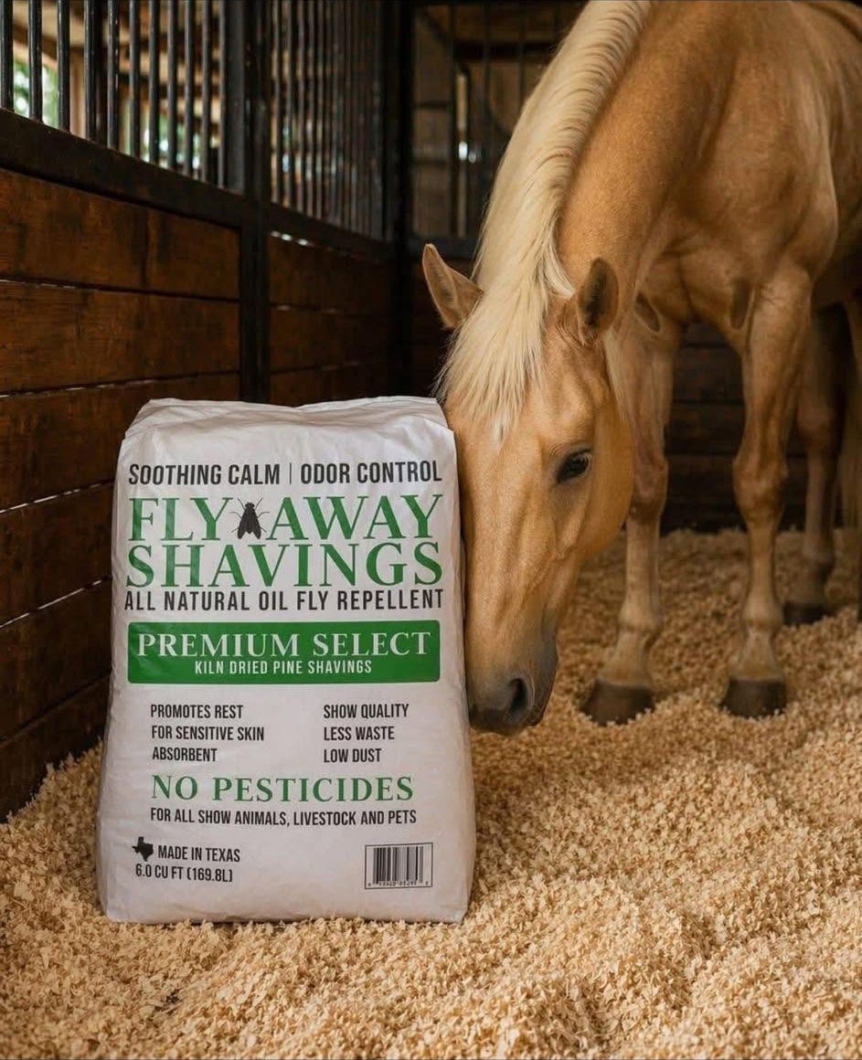 Bag of Fly Away Shavings beside a palomino horse in a bedded stall